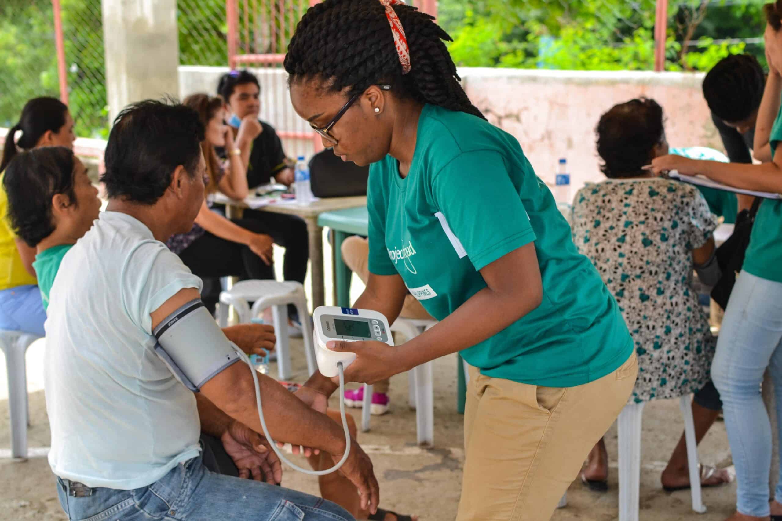 A Public Health volunteer takes the blood pressure of a local man during a medical outreach