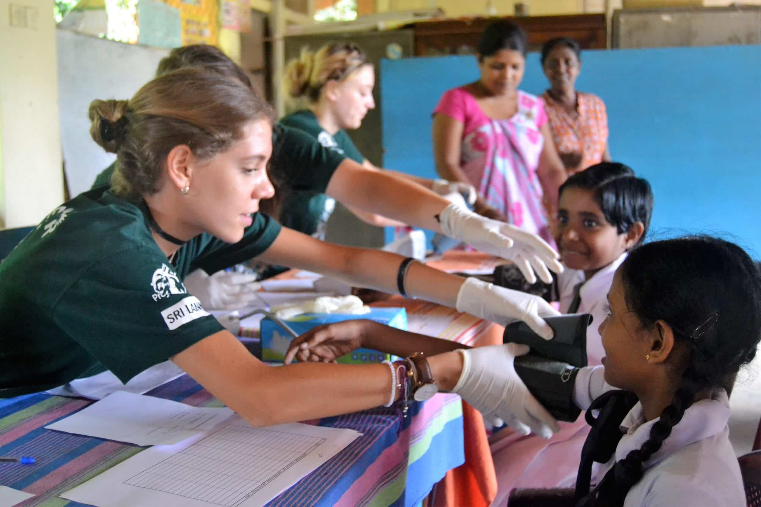 Healthcare volunteers checking the blood pressure of children in Sri Lanka during their time abroad