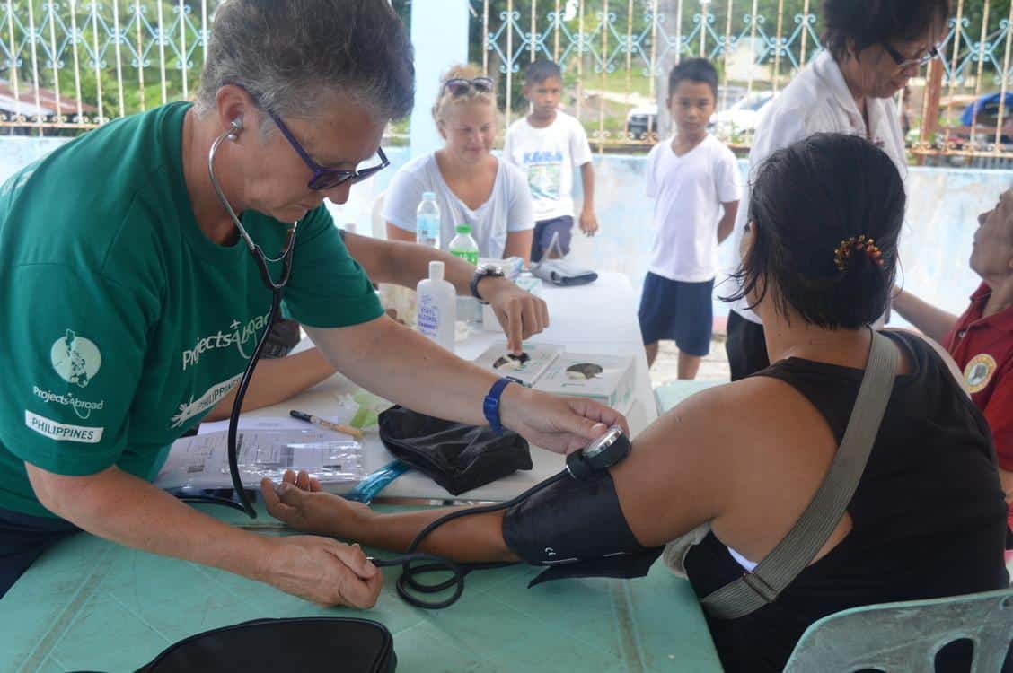 Healthcare volunteer measures the blood pressure of a local as part of her voluntary work for pensioners