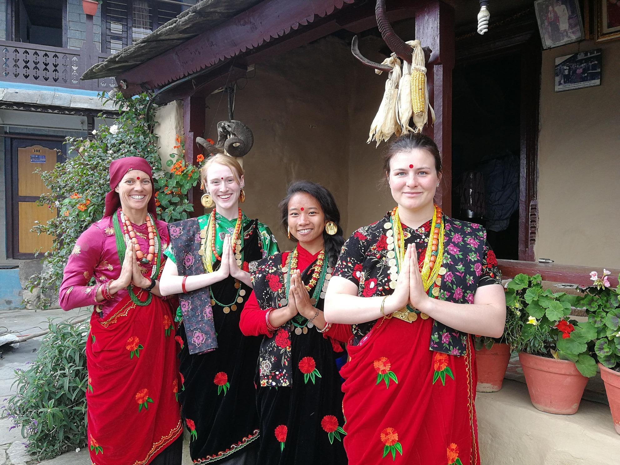 Projects Abroad volunteers and their host family dressed in bright, traditional Nepali clothes