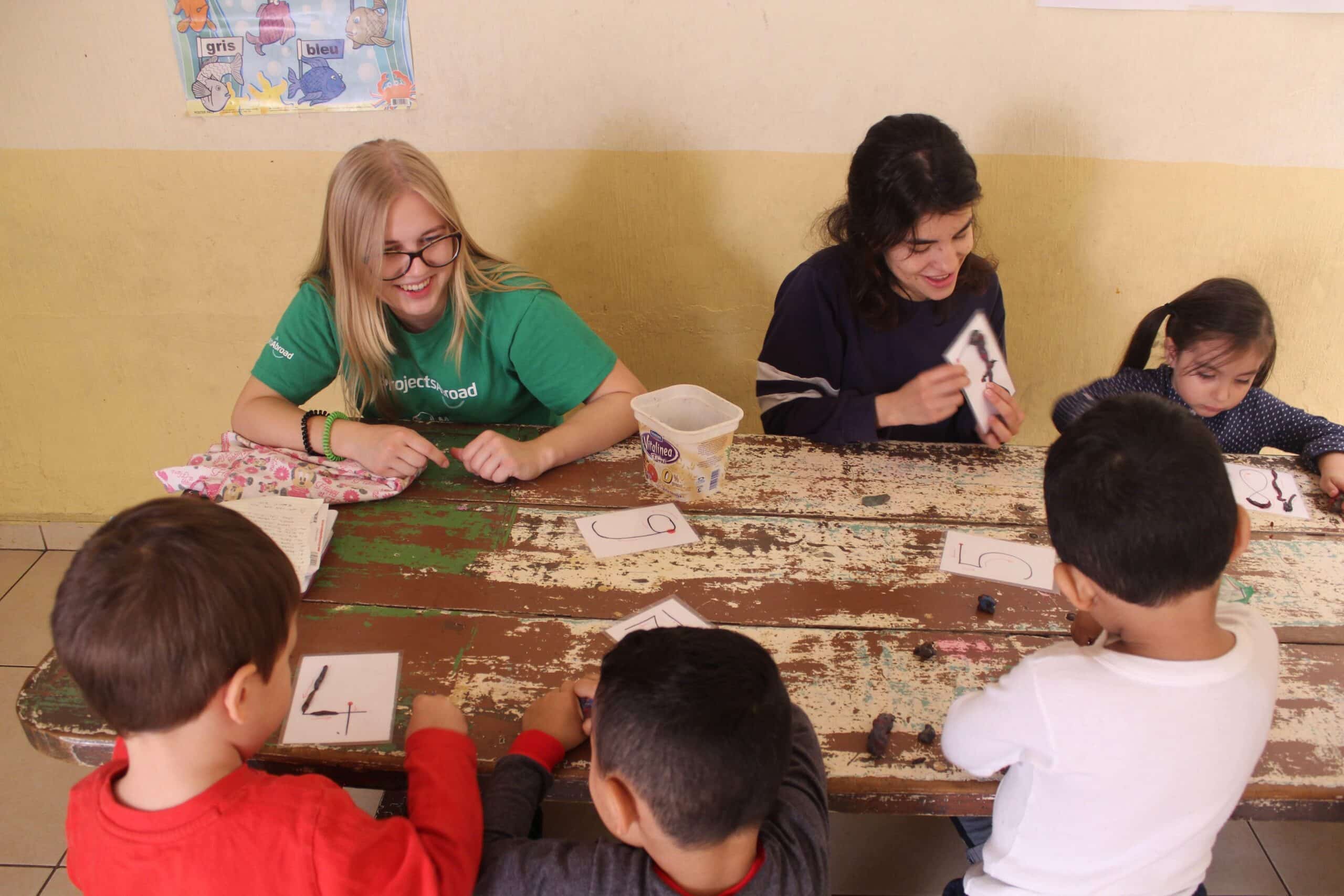 Swiss volunteer Laurane helping to teach the numbers to little children.