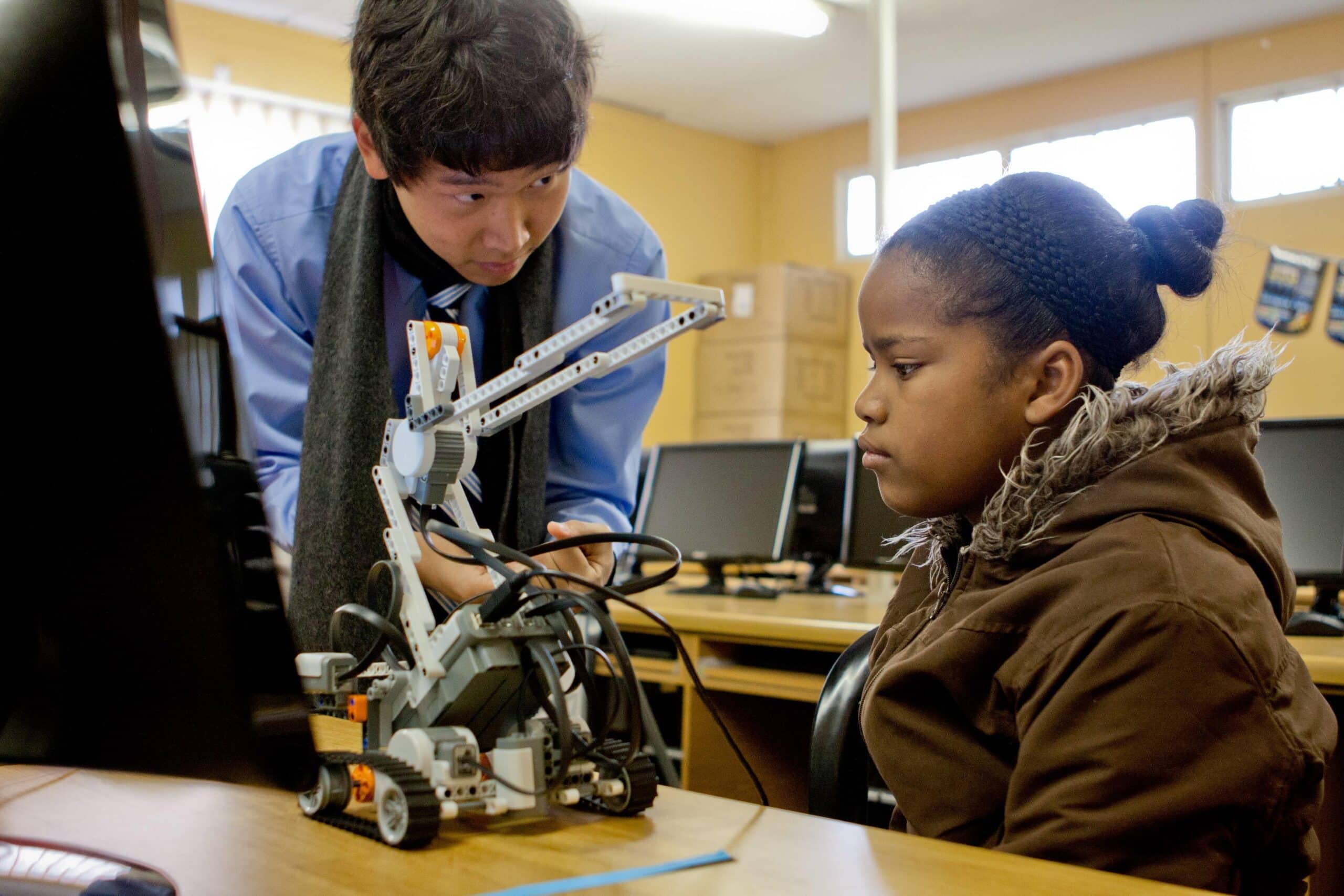 An IT teaching volunteer shows the functionality of a small robot to a girl in Ghana during his internship with Projects Abroad.