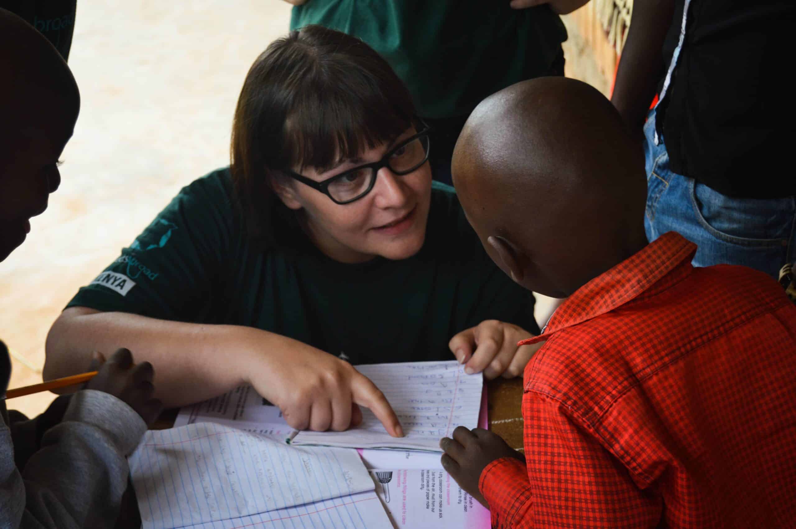 A Projects Abroad teaching volunteer helps children in Kenya with their school lesson.