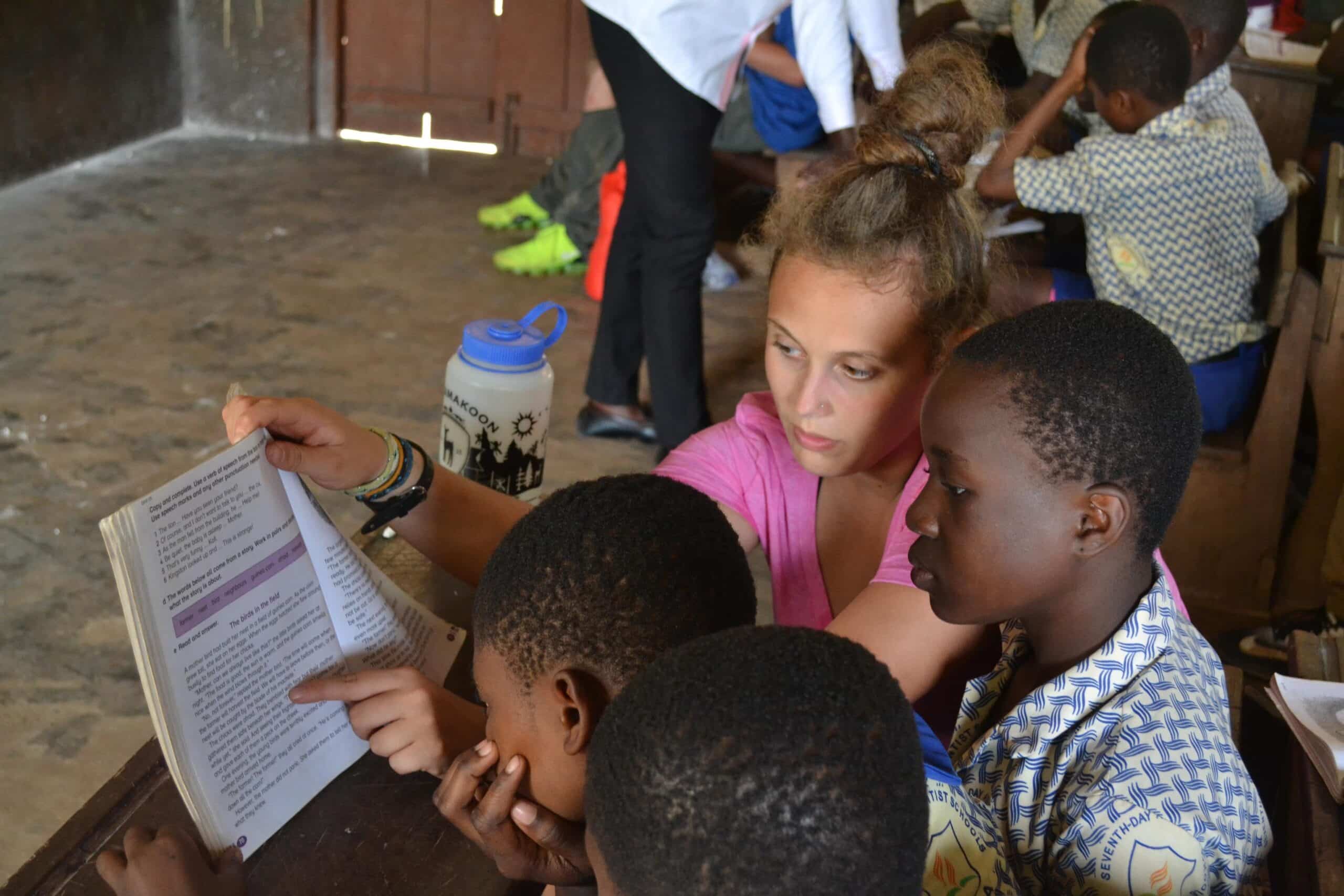 A Projects Abroad volunteer explains a text to some students in Ghana during her teaching English internship.