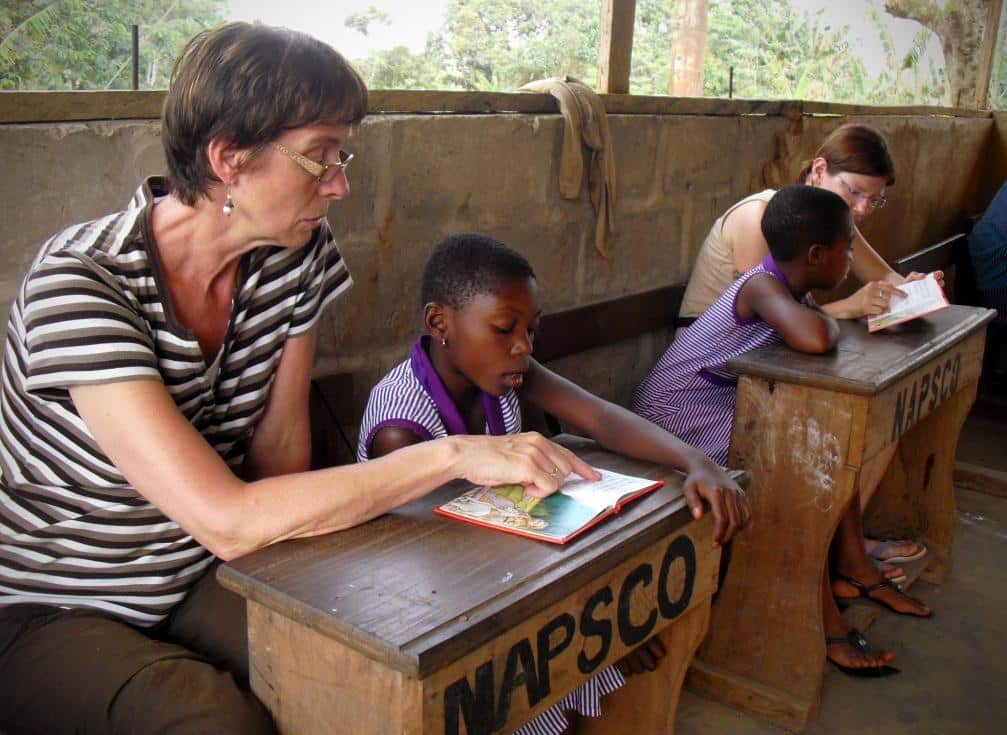 A couple of volunteers doing a teaching English project in Ghana with Projects Abroad participate in a reading club.