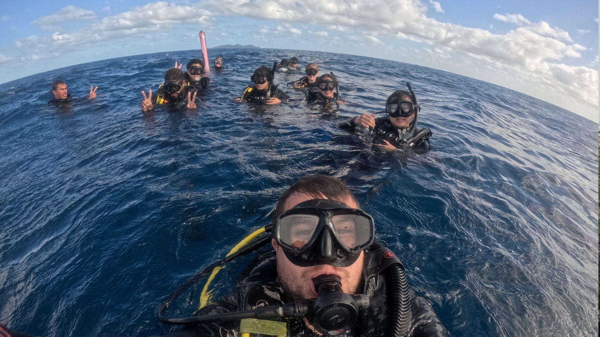 A group of Projects Abroad volunteers in full diving gear swim off the coast of Fiji while protecting endangered shark species